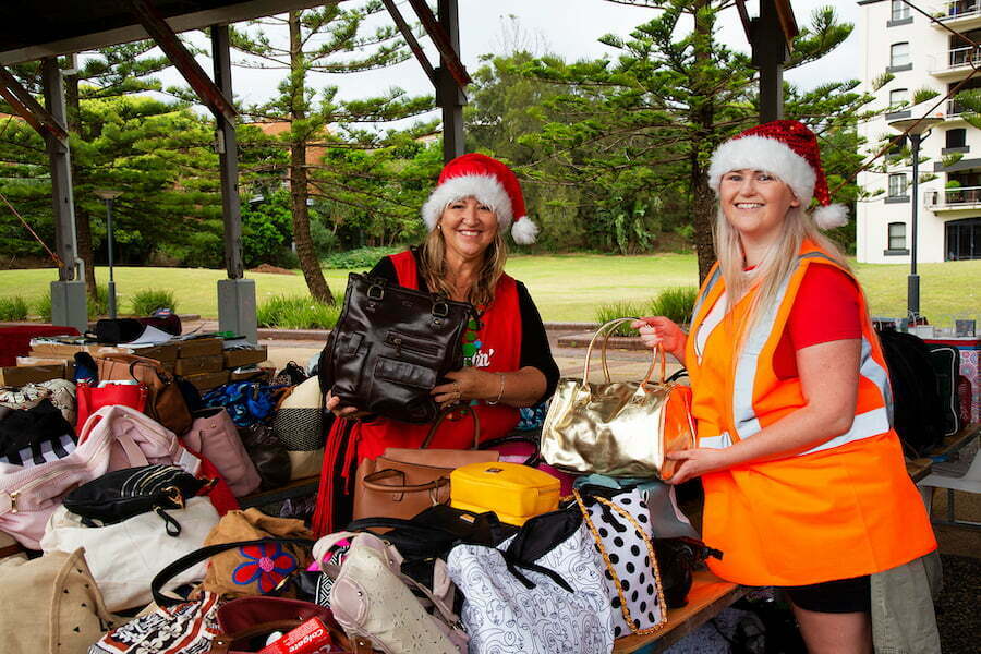 Two volunteers in Santa hats pack Christmas gifts and hampers