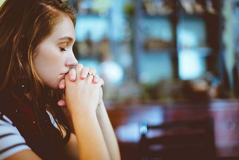 A young woman solemnly praying in the church