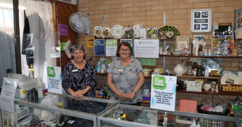 Two volunteers stand behind a counter in a Samaritans Op Shop