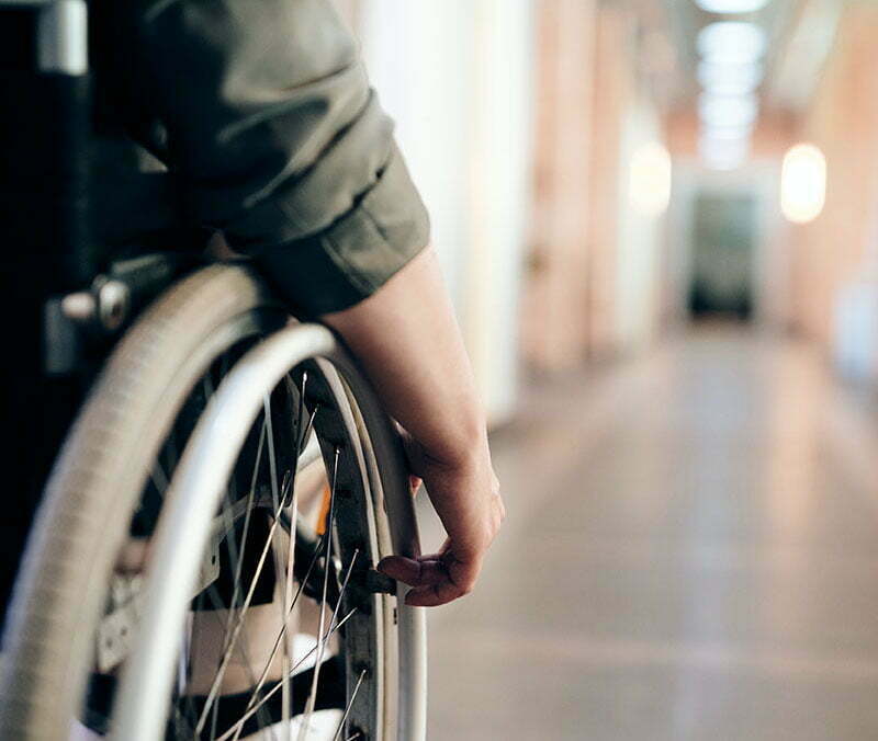 A person wheeling their wheelchair down a corridor