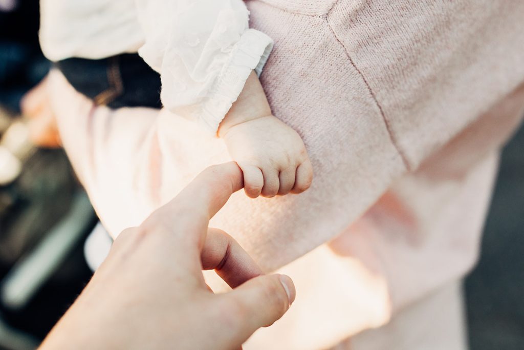 Baby's hand holding woman's index finger