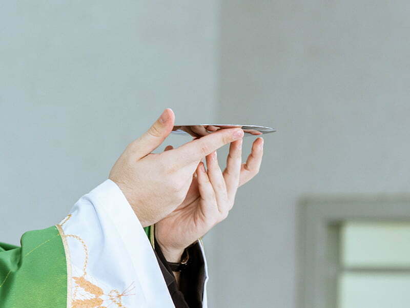 A priest's hands holding first communion 