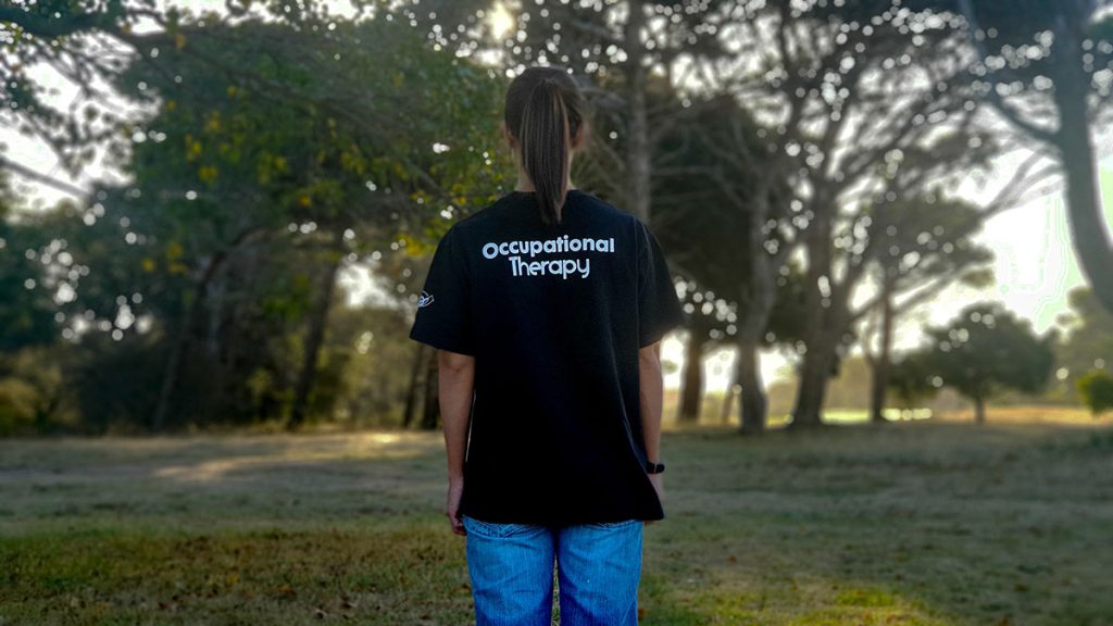 A woman wearing a black shirt with 'Occupational Therapy' printed on the back of her shirt