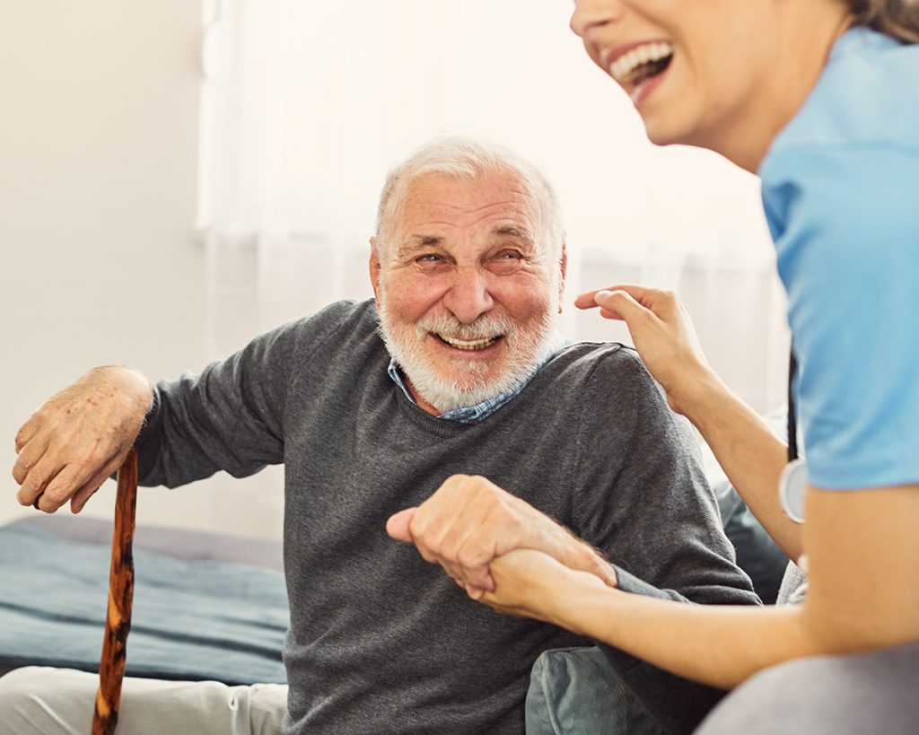 Elderly man with a cane laughs with a young woman